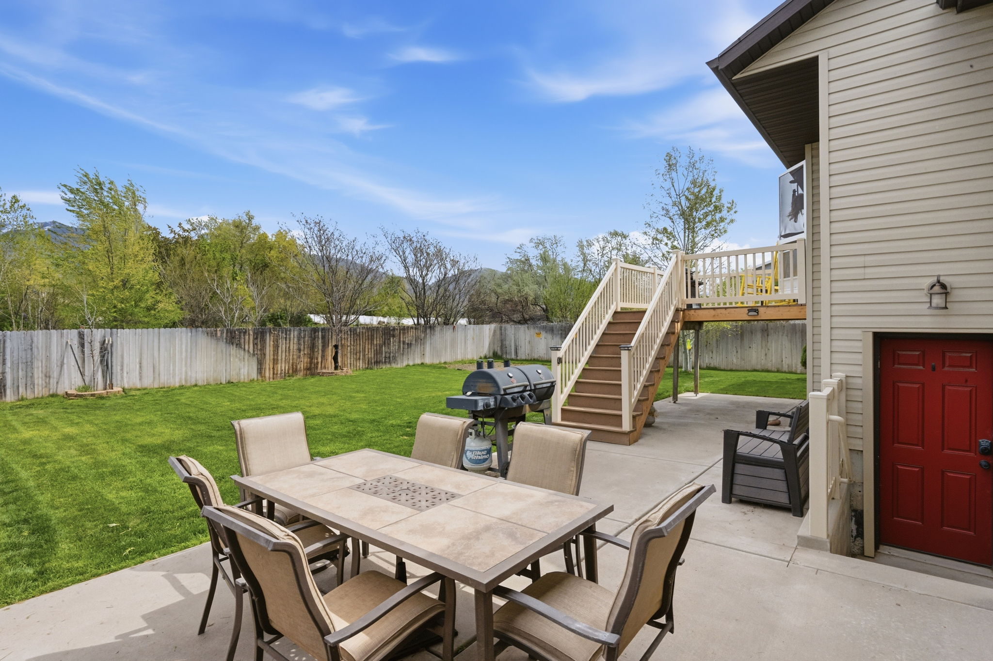 Fenced backyard with outdoor dining area, a patio area, a grill, and a deck