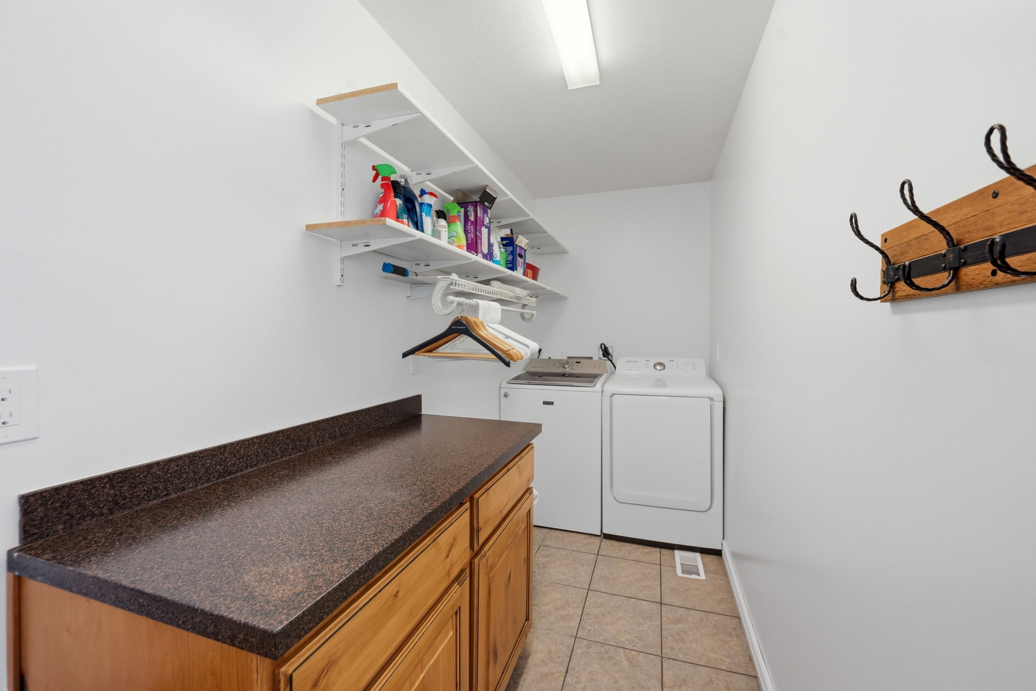 Laundry area with light tile patterned floors and cabinet space