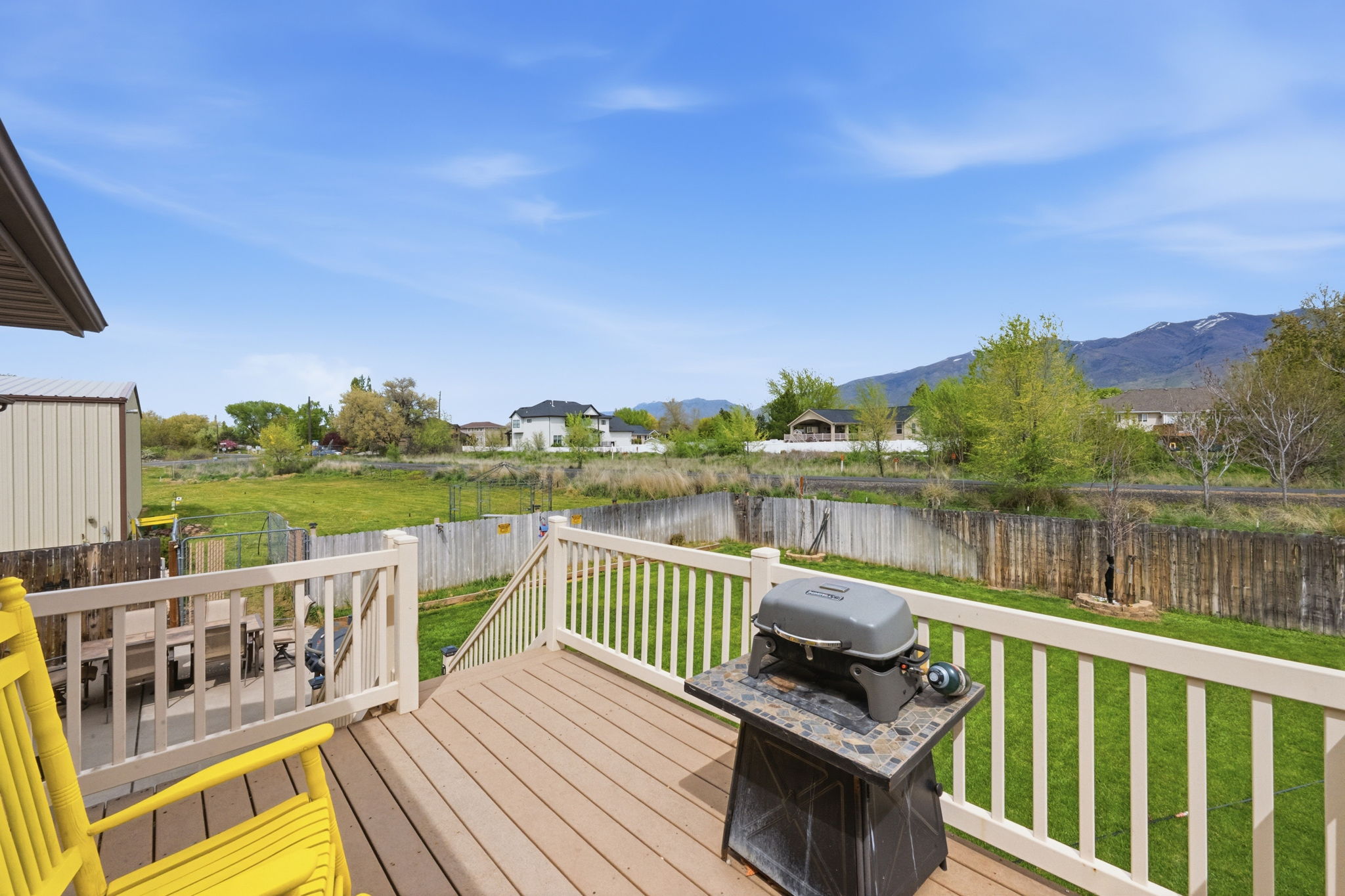 Deck with a residential view, a fenced backyard, grilling area, and a mountain view