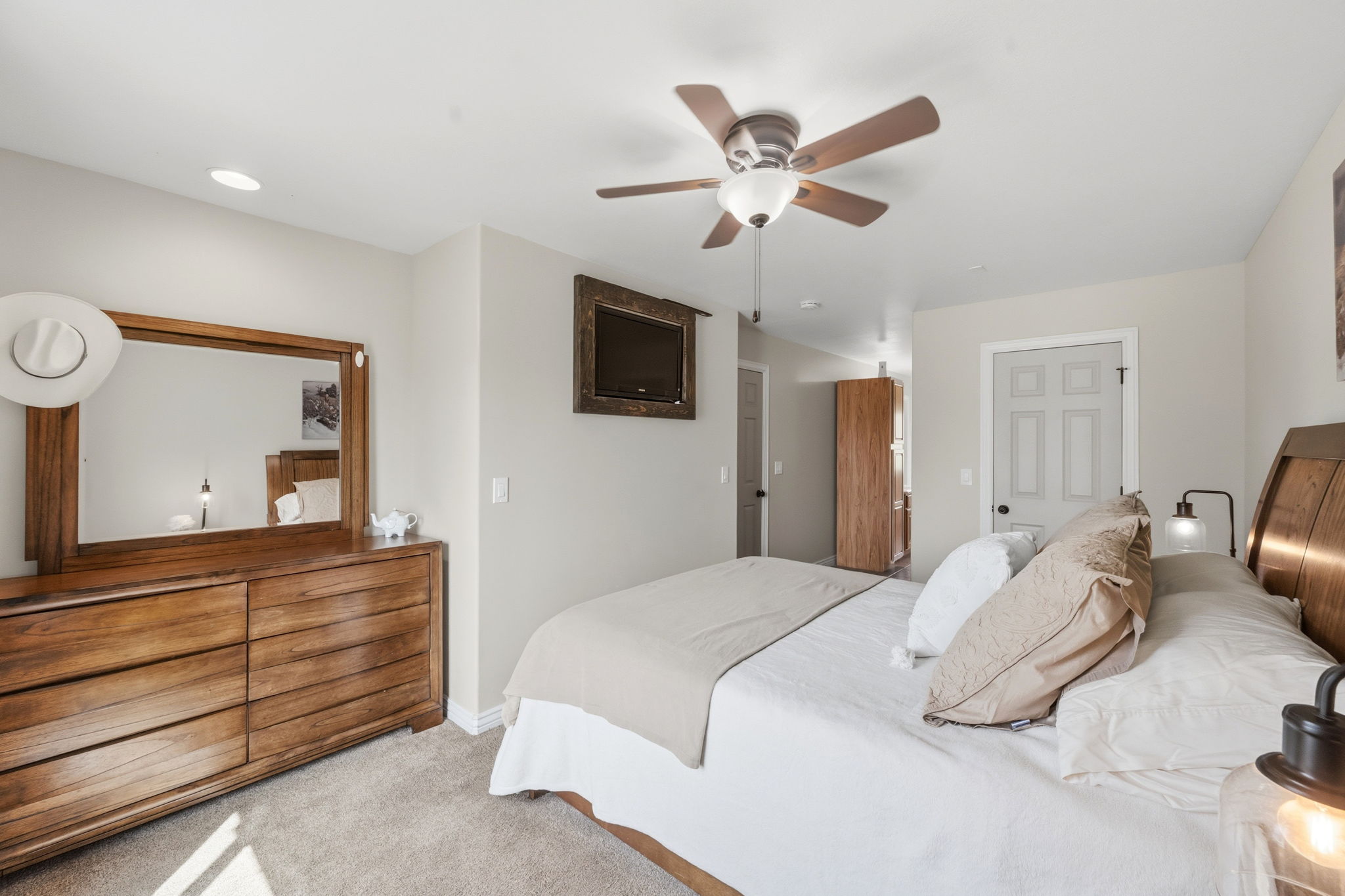 Primary Bedroom with light carpet, ceiling fan, and a walk-in closet