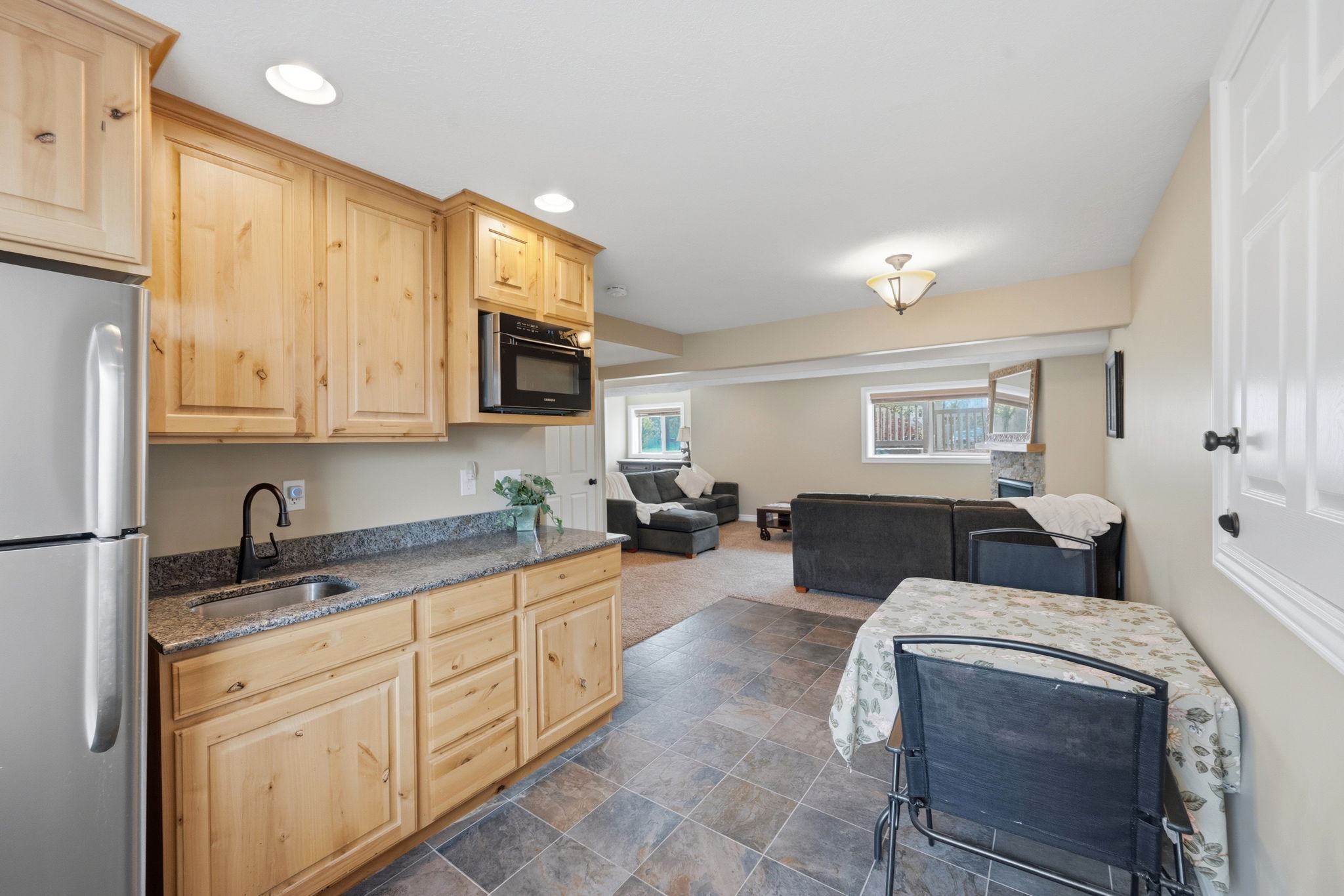 Kitchen with light wood finish cabinetry, freestanding refrigerator, open floor plan, recessed lighting, and dark countertops