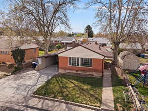 View of front facade with a residential view, an attached carport, driveway, a playground, and a shed