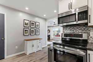 Kitchen featuring stainless steel appliances, white cabinetry, butcher block countertops, a ceiling fan, and tasteful backsplash