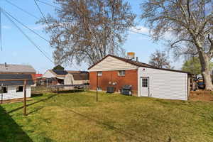 Back of house with a chimney, a yard, and brick siding