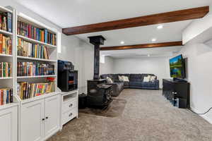 Living room featuring recessed lighting, dark colored carpet, beam ceiling, and a wood stove