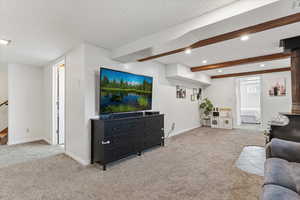 Living area featuring light carpet, beamed ceiling, a textured ceiling, and recessed lighting