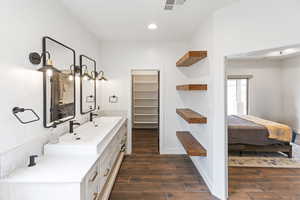 Ensuite bathroom with double vanity, dark wood-style floors, a spacious closet, and recessed lighting
