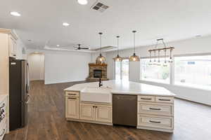 Kitchen featuring cream cabinetry, a ceiling fan, arched walkways, stainless steel appliances, and a stone fireplace