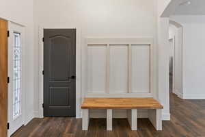 Mudroom with arched walkways and dark wood-style floors