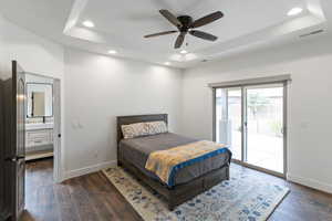 Bedroom with dark wood-style flooring, recessed lighting, access to exterior, a raised ceiling, and a ceiling fan