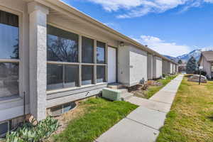 View of side of property featuring a lawn, a mountain view, and stucco siding