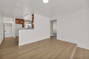 Unfurnished living room featuring light wood finished floors and baseboards