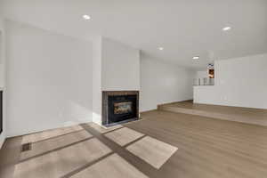 Unfurnished living room with a tiled fireplace, light wood-style flooring, and recessed lighting