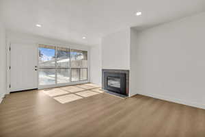 Unfurnished living room featuring light wood-style flooring, recessed lighting, and a tiled fireplace
