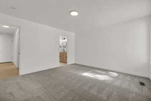 Unfurnished bedroom with light carpet and connected bathroom