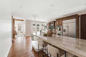 Kitchen with a breakfast bar area, light countertops, stainless steel appliances, dark wood-style floors, and pendant lighting