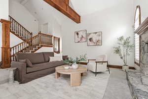 Living room with light colored carpet, lofted ceiling, and a fireplace with raised hearth