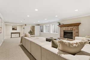 Living room featuring crown molding, recessed lighting, light colored carpet, and a brick fireplace