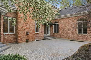 Back of property featuring brick siding, a shingled roof, and a patio