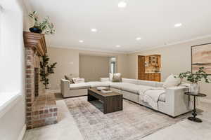 Living room with light carpet, recessed lighting, a fireplace, and ornamental molding