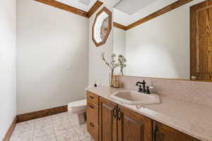 Half bath featuring vanity, crown molding, and light tile patterned floors