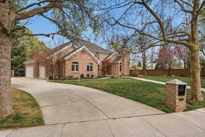 View of front of home featuring brick siding, a chimney, and driveway