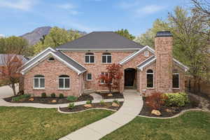 View of front of house featuring brick siding, a chimney, and a mountain view
