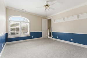 Empty room featuring light carpet, ceiling fan, and ornamental molding