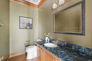 Bathroom with vanity, crown molding, and wood finished floors