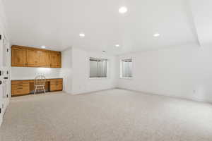 Unfurnished office with built in desk, light carpet, and recessed lighting