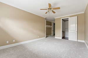 Unfurnished bedroom featuring carpet floors, ornamental molding, a ceiling fan, and connected bathroom