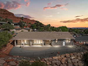 Back of house at dusk featuring a fenced backyard and stone siding