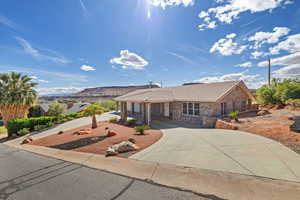 Single story home featuring a tile roof, stone siding, and driveway