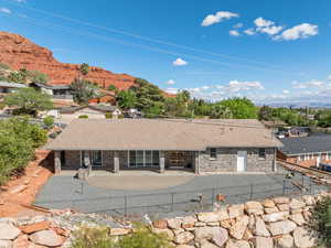 Rear view of house with a fenced backyard, stone siding, a mountain view, and a patio