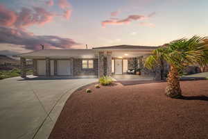 View of front of property with a garage, concrete driveway, brick siding, and a patio