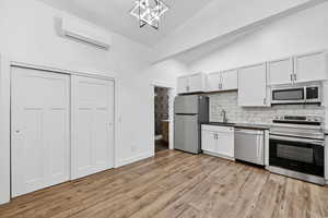 Kitchen with stainless steel appliances, dark countertops, vaulted ceiling, white cabinetry, and a chandelier