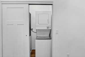 Laundry area featuring stacked washer / dryer and dark wood finished floors