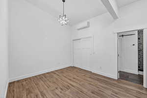 Unfurnished dining area featuring a barn door, wood finished floors, lofted ceiling, and a chandelier