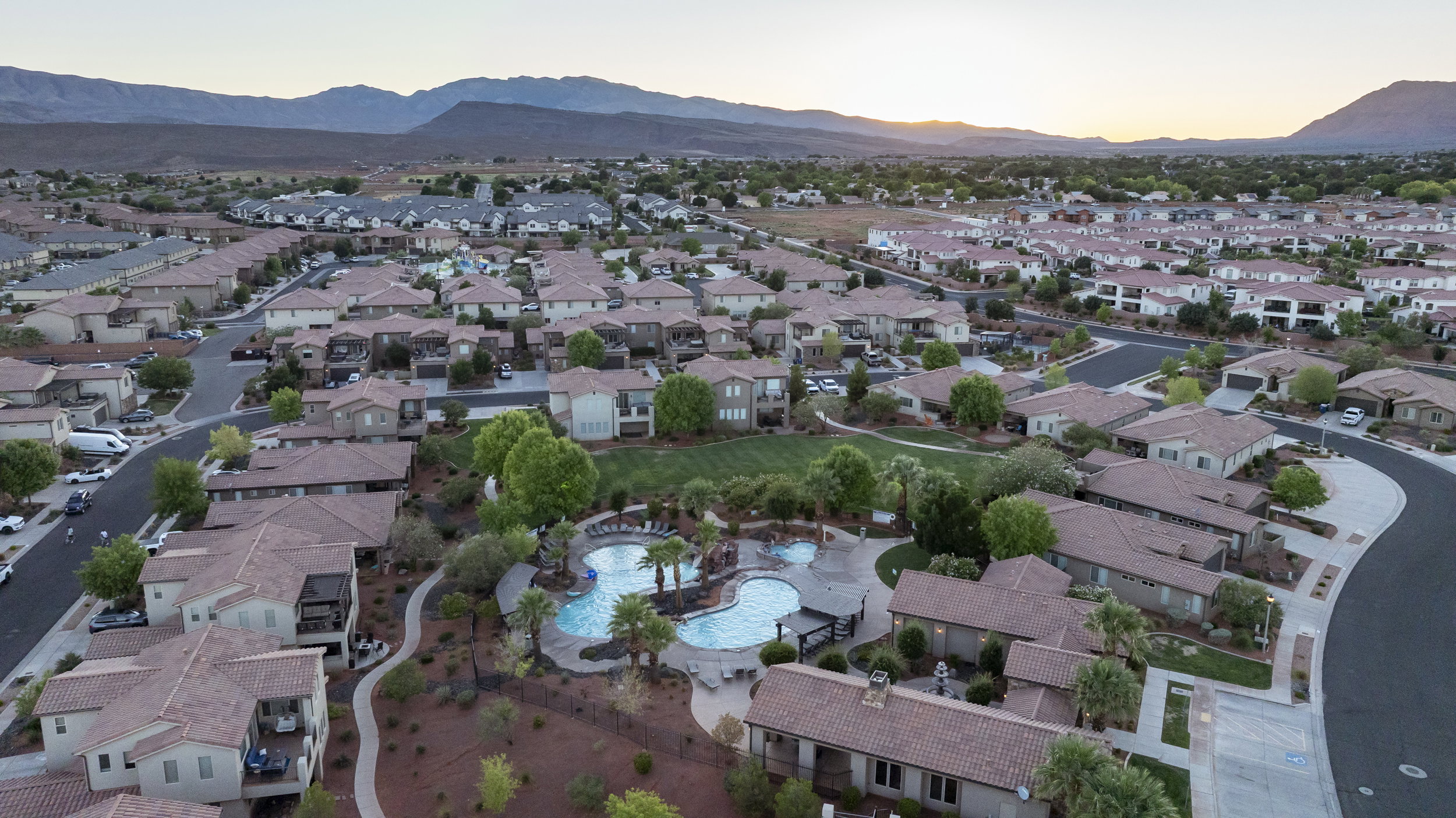 Aerial view at dusk of a residential view, a mountain view, and view of pool area