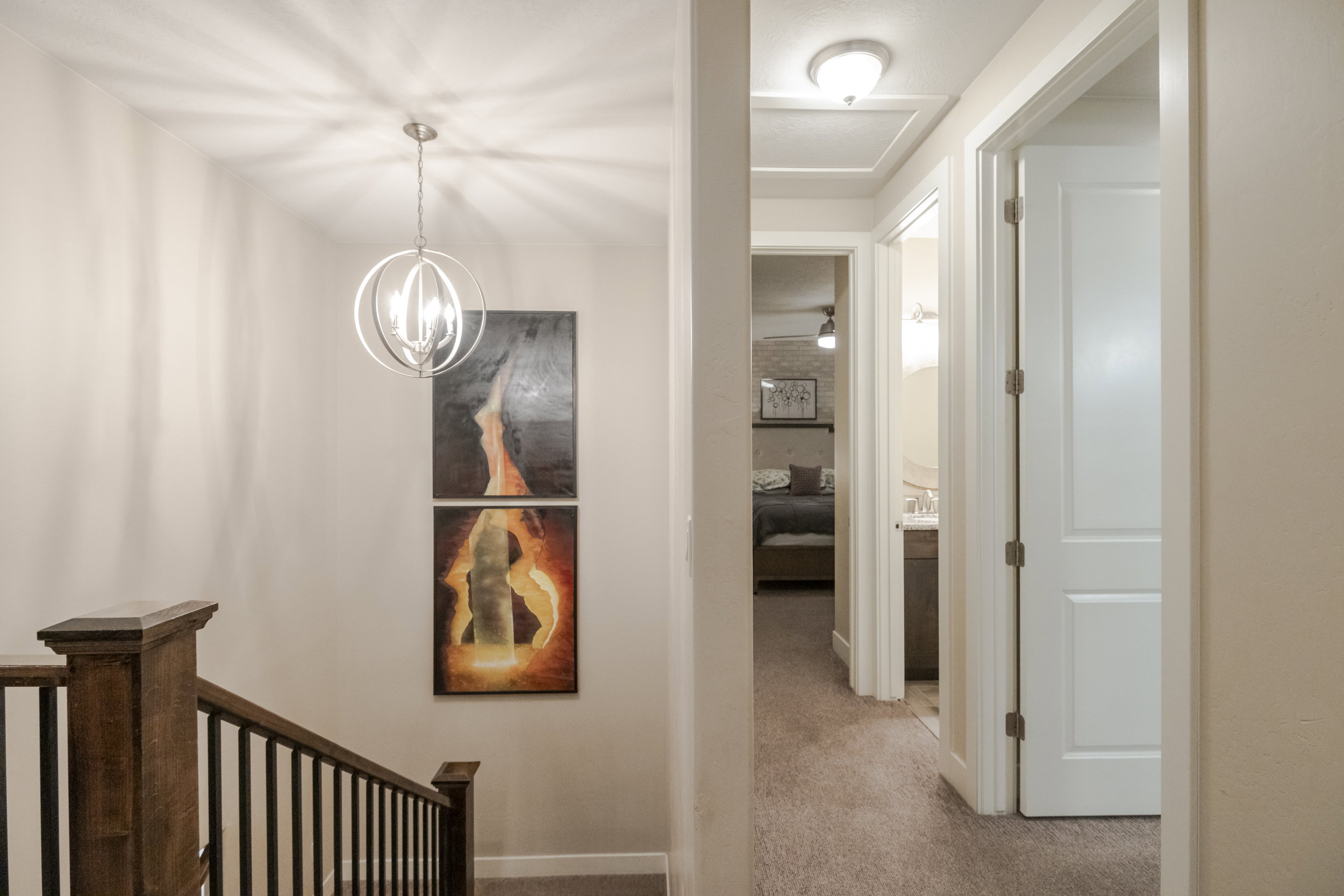 Corridor featuring light colored carpet and hanging lights