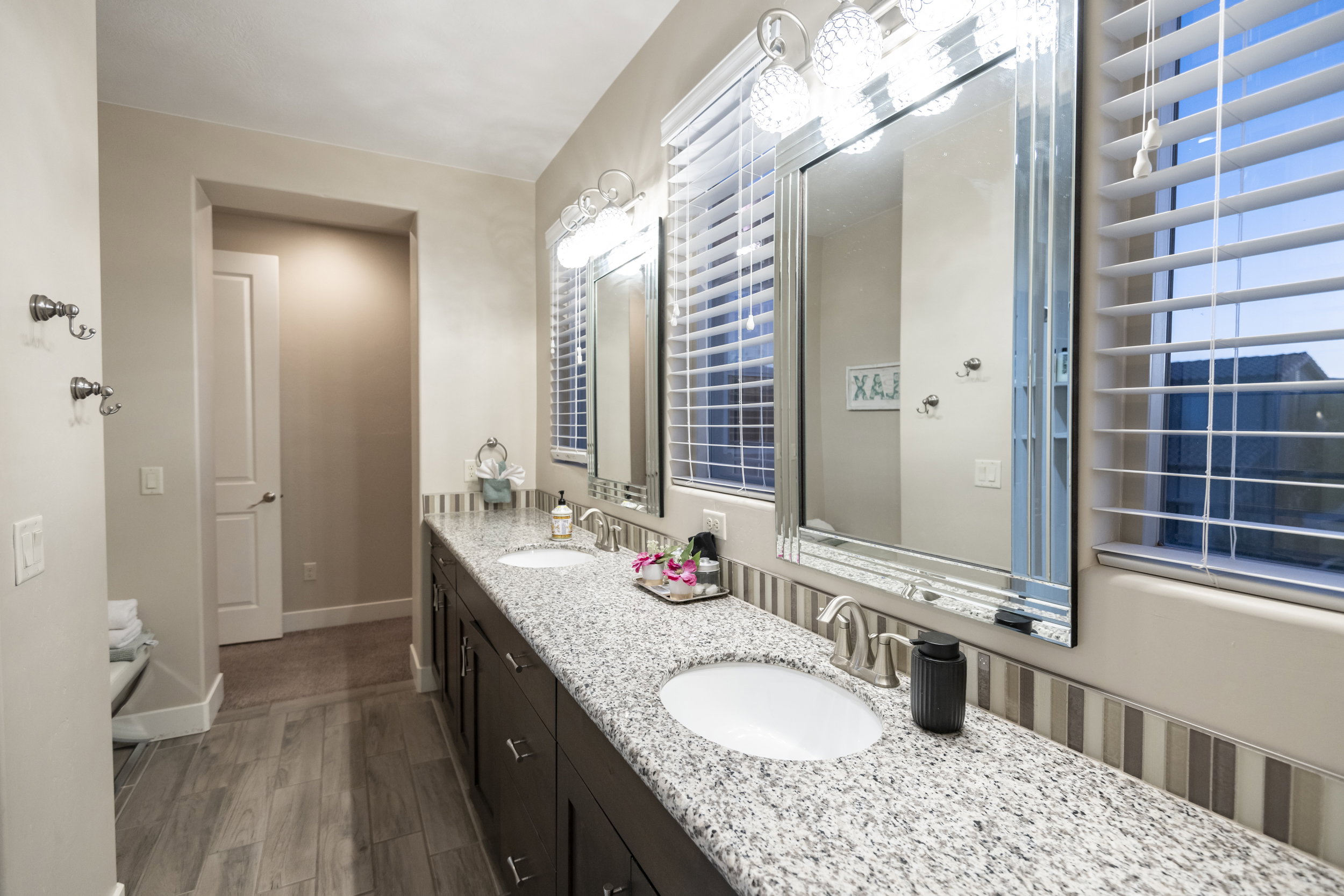 Full bath featuring double vanity and dark wood-style flooring