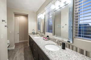 Full bath featuring double vanity and dark wood-style flooring