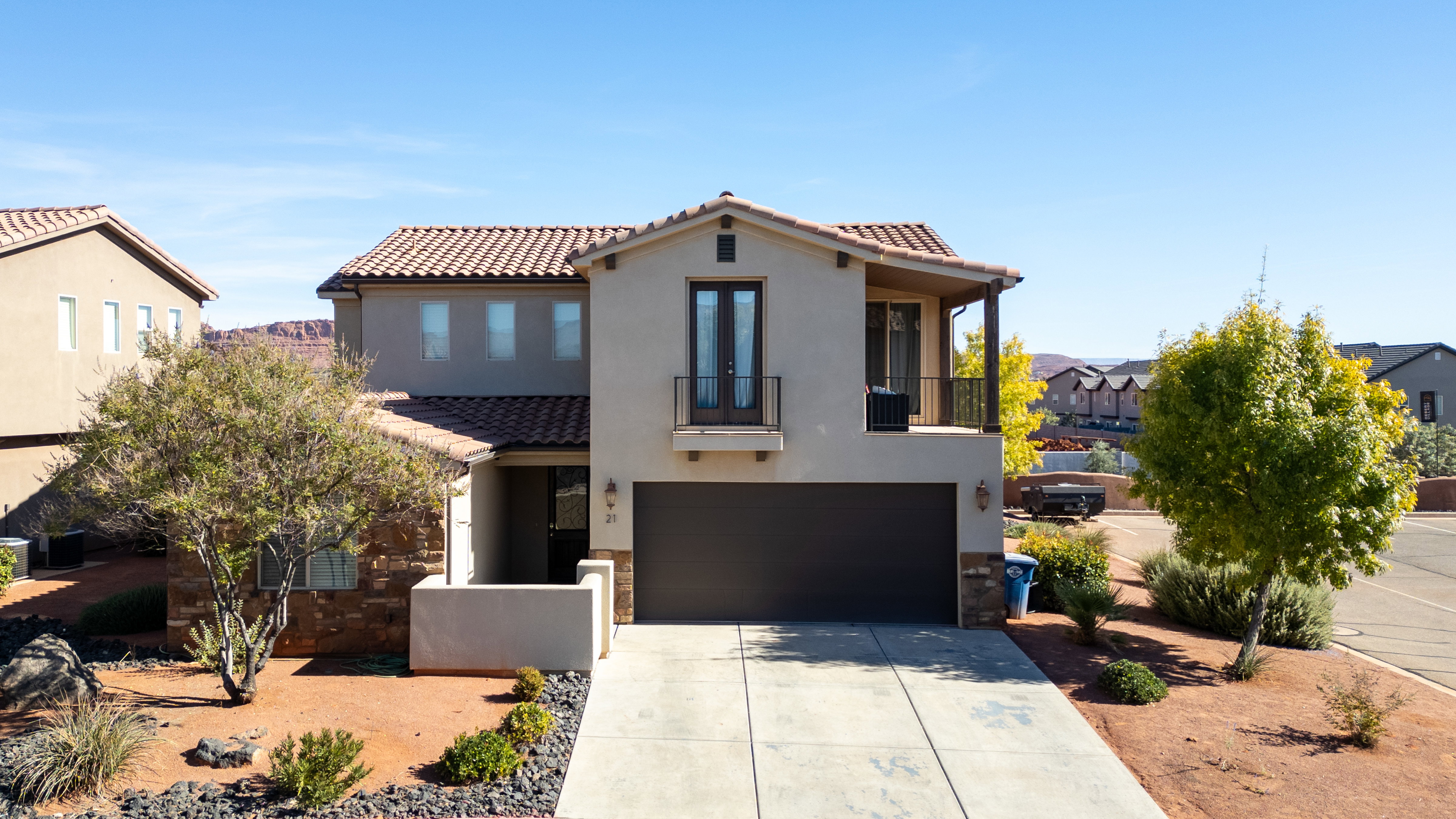Mediterranean / spanish-style home featuring a balcony, a garage, driveway, stucco siding, and a tile roof