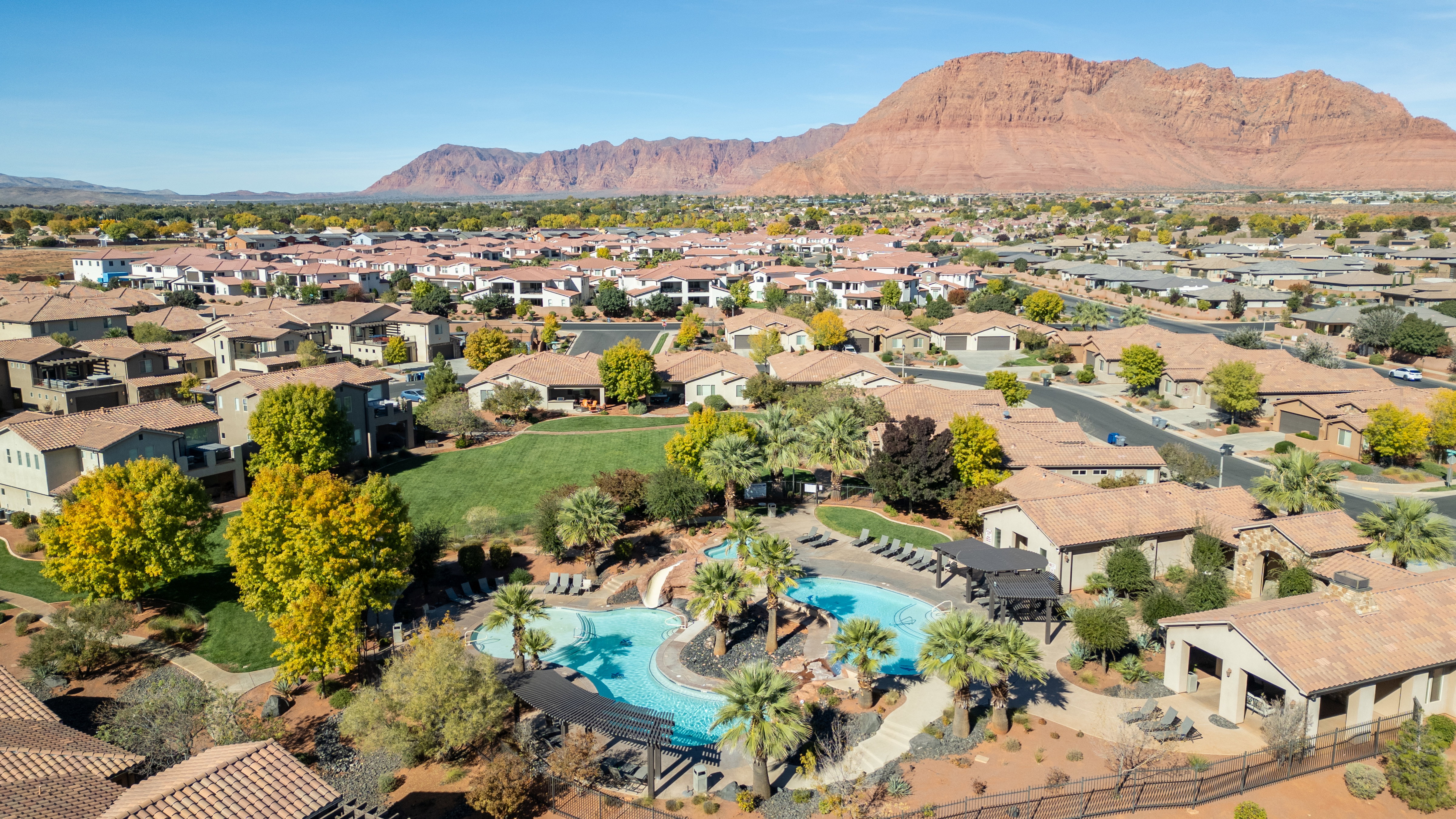 Aerial view of residential area featuring a mountain backdrop and a pool