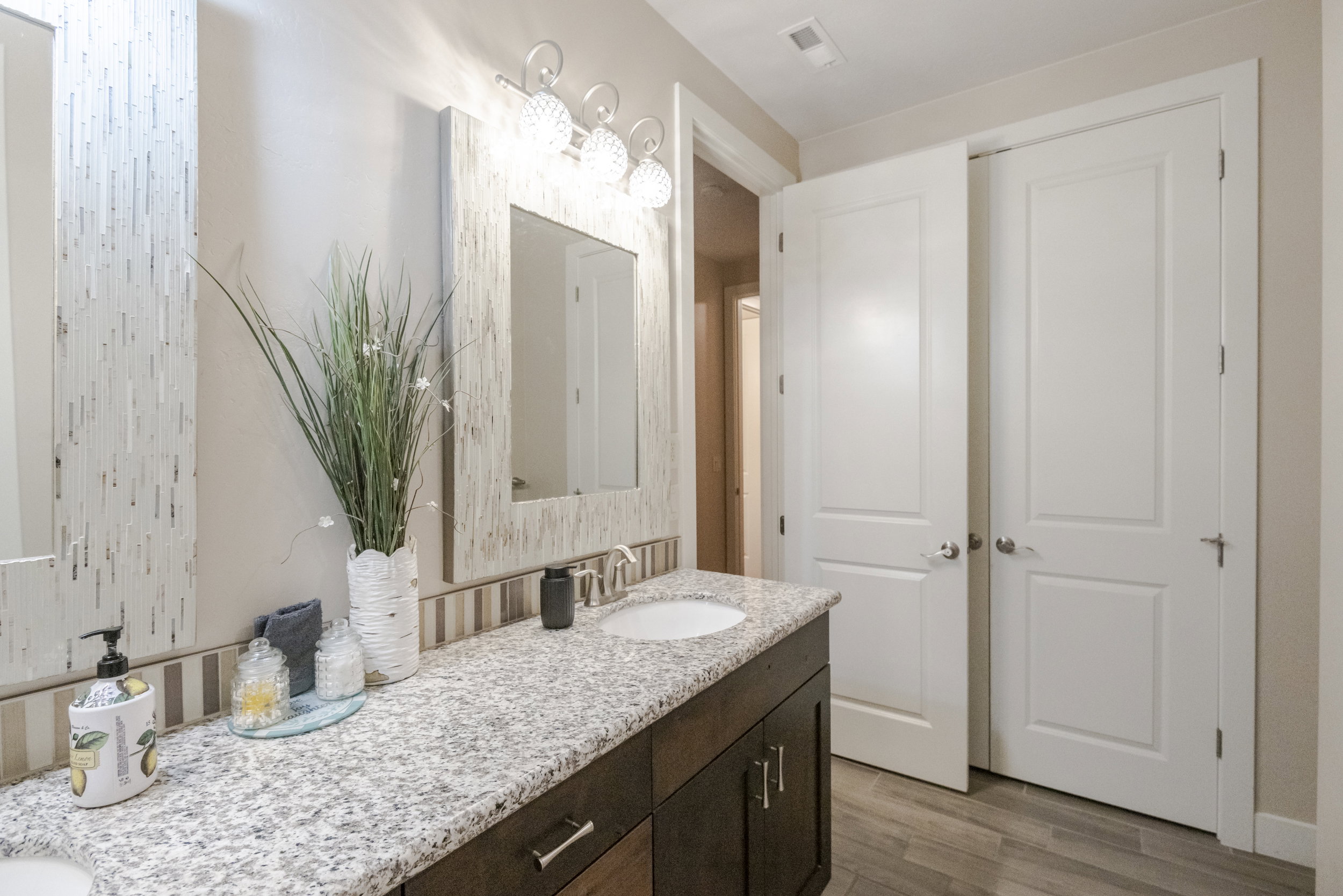 Full bath with double vanity and light wood finished floors