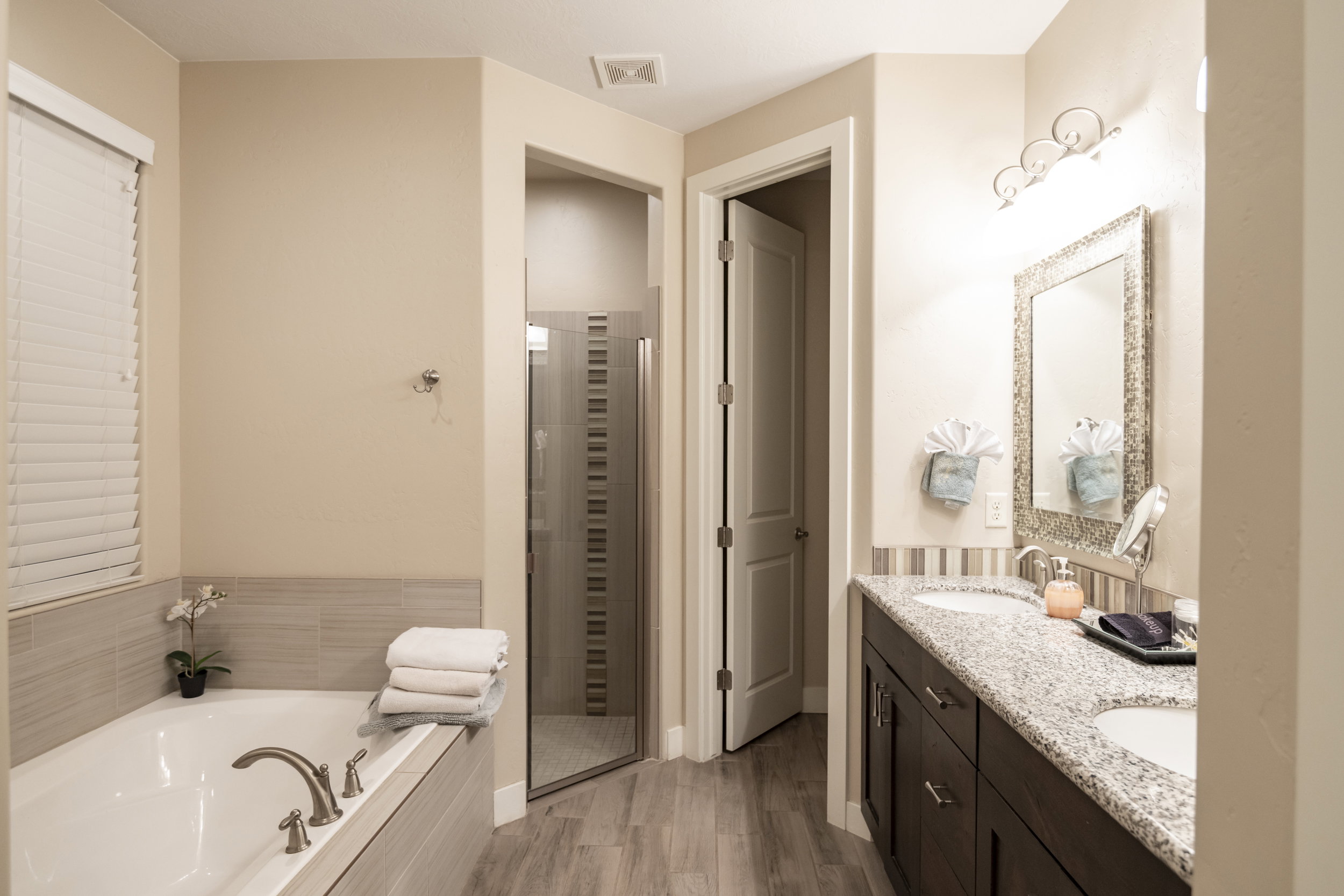 Bathroom featuring double vanity, a garden tub, a shower stall, and light wood-style flooring