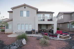 Rear view of property featuring a patio area, an outdoor living space with a fire pit, a tile roof, and stucco siding