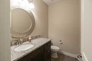 Half bath with vanity and dark wood-style flooring