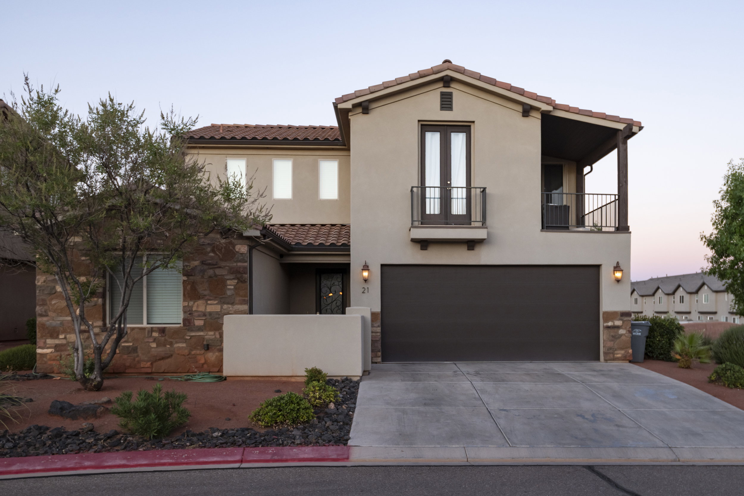 Mediterranean / spanish house featuring a balcony, a tiled roof, stone siding, a garage, and stucco siding