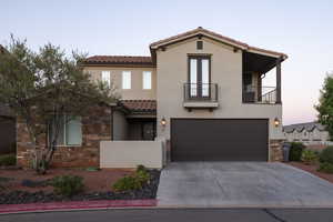 Mediterranean / spanish house featuring a balcony, a tiled roof, stone siding, a garage, and stucco siding